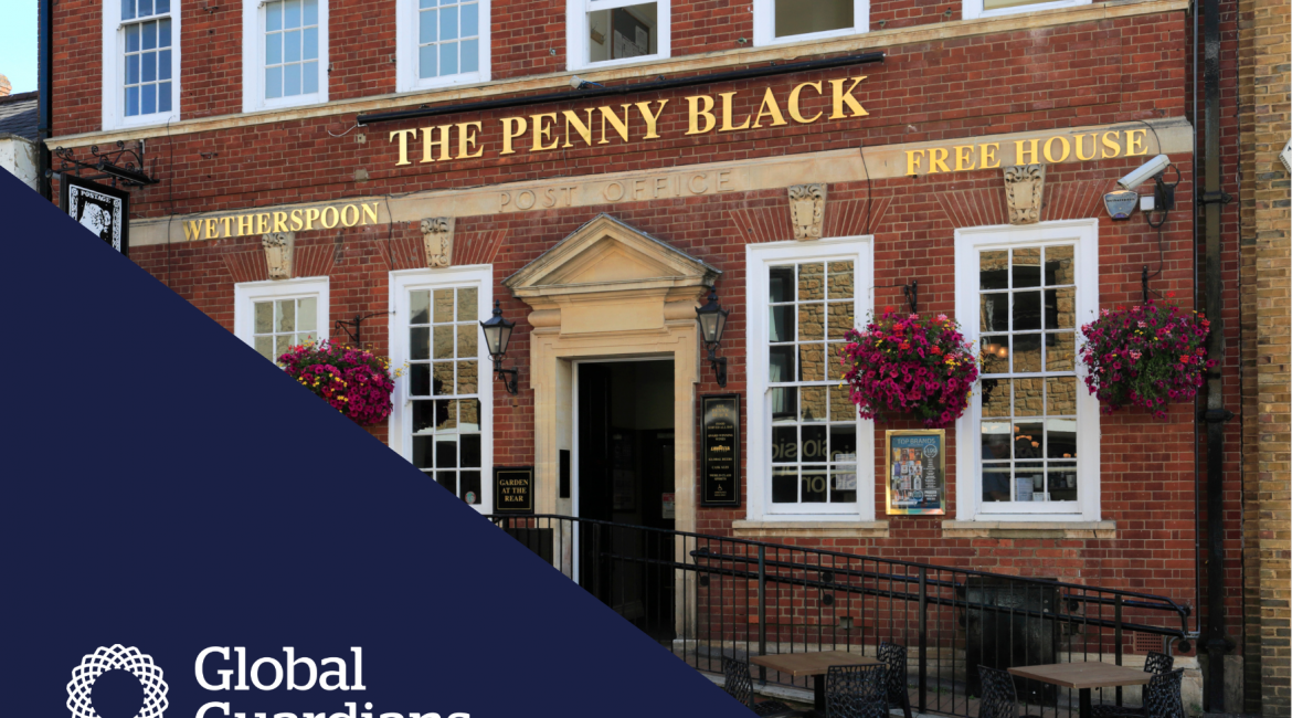 The outside of a traditional british pub with a number of white silled windows. It's called The Penny Black, and it is written on a sign with gold lettering.