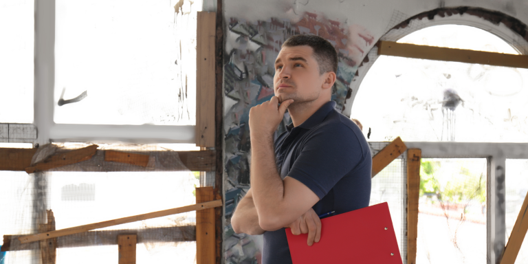 how to maintain an empty property, an inspector looking at an abandoned room in a building holding a clipboard